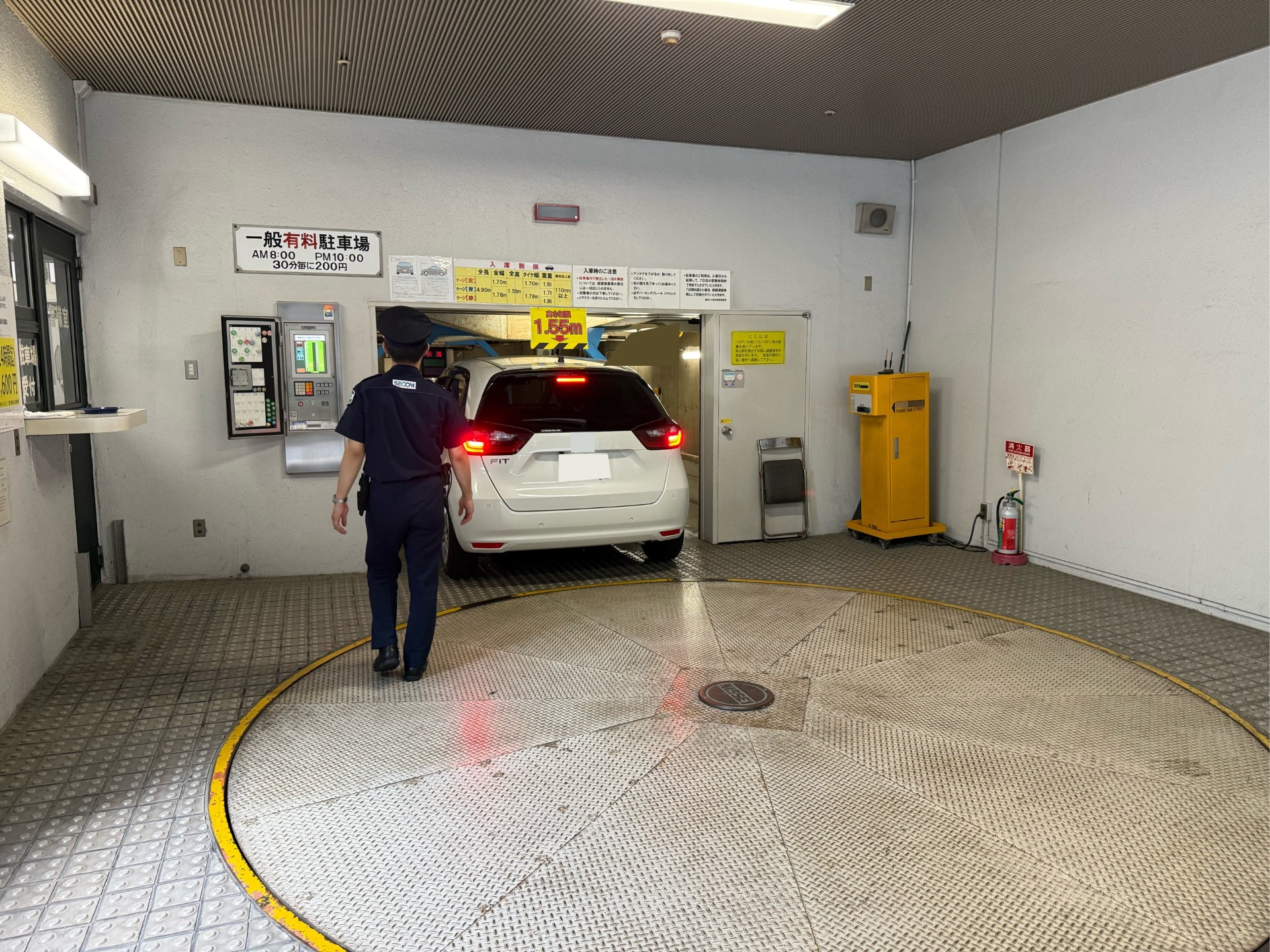 機械式駐車場に入庫する車と誘導するスタッフ